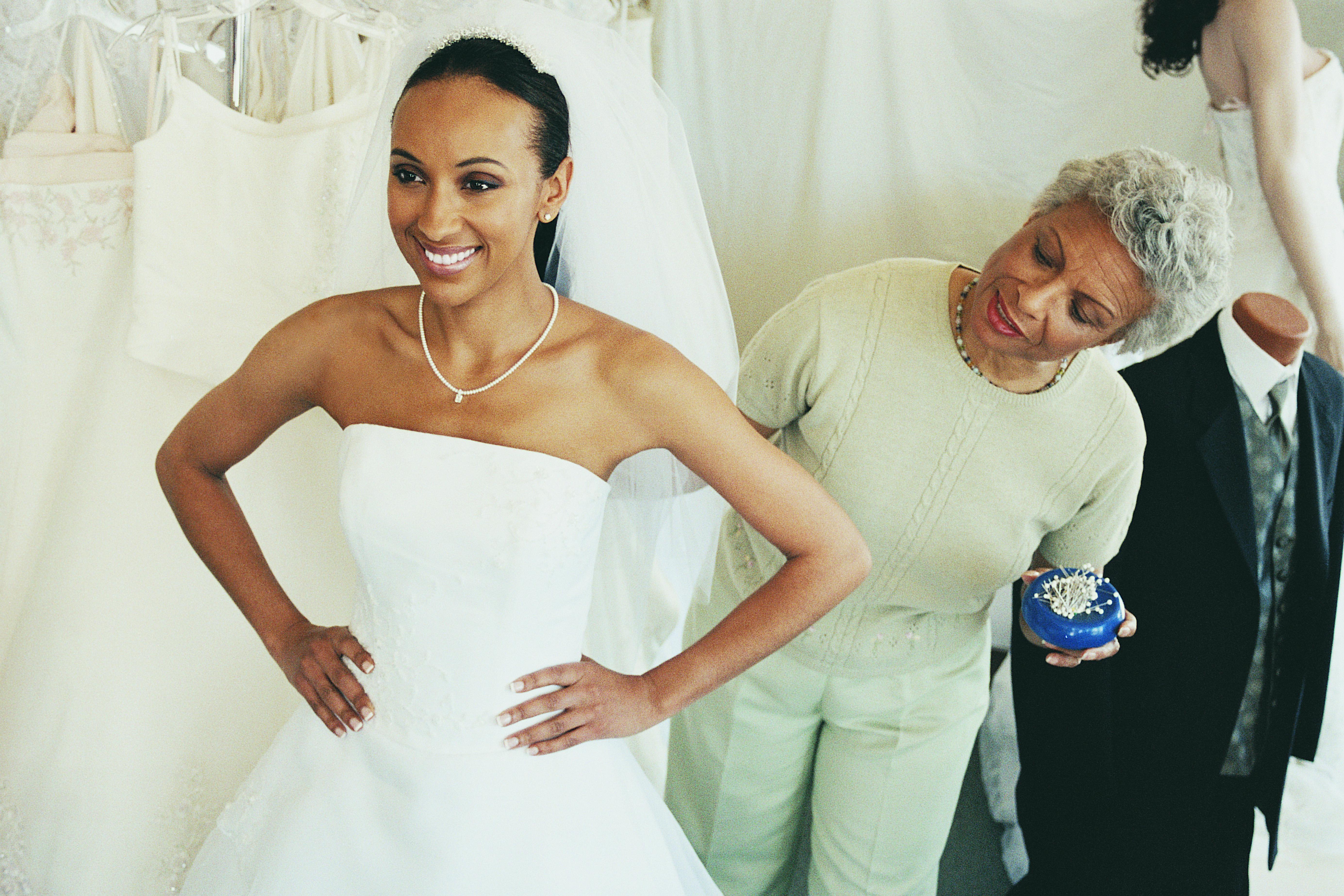 Shop Assistant Helping a Woman Try on a Wedding Dress in a Clothes Shop