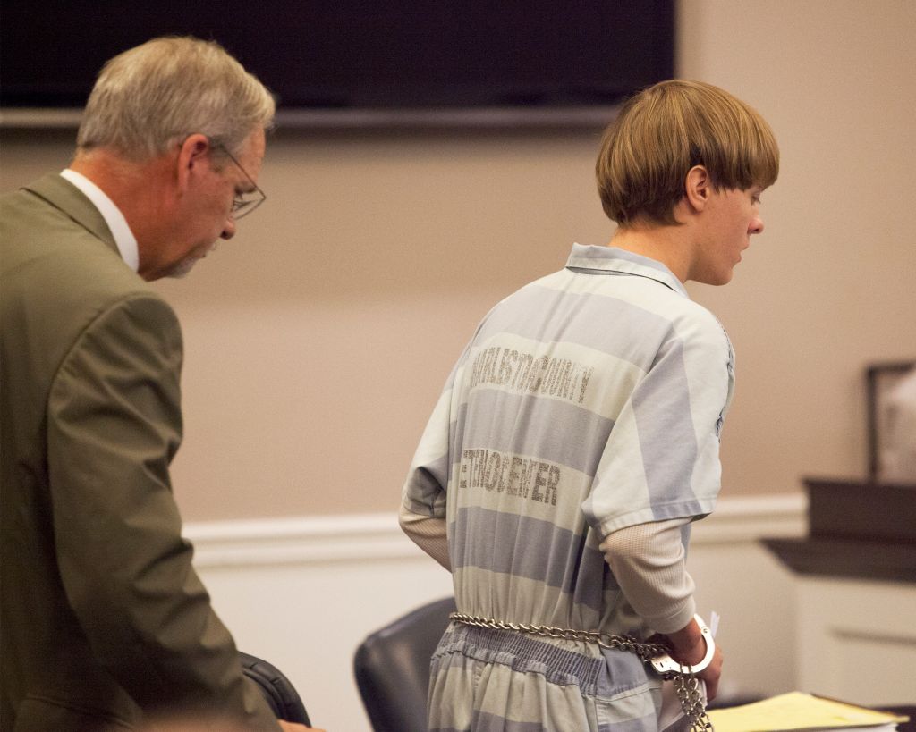 Dylann Roof (R), the 21-year-old man charged with murdering nine worshippers at a historic black church in Charleston last month, is helped to his chair by chief public defender Ashley Pennington during a hearing at the Judicial Center in Charleston