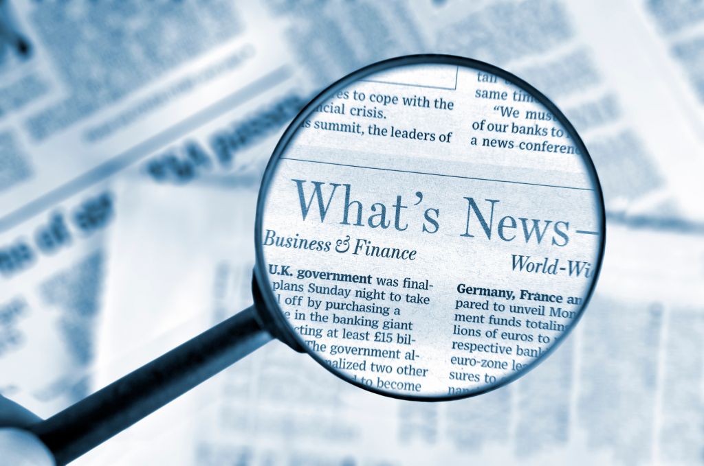 Close-up on magnifying glass above Wall Street Journal newspaper, blue