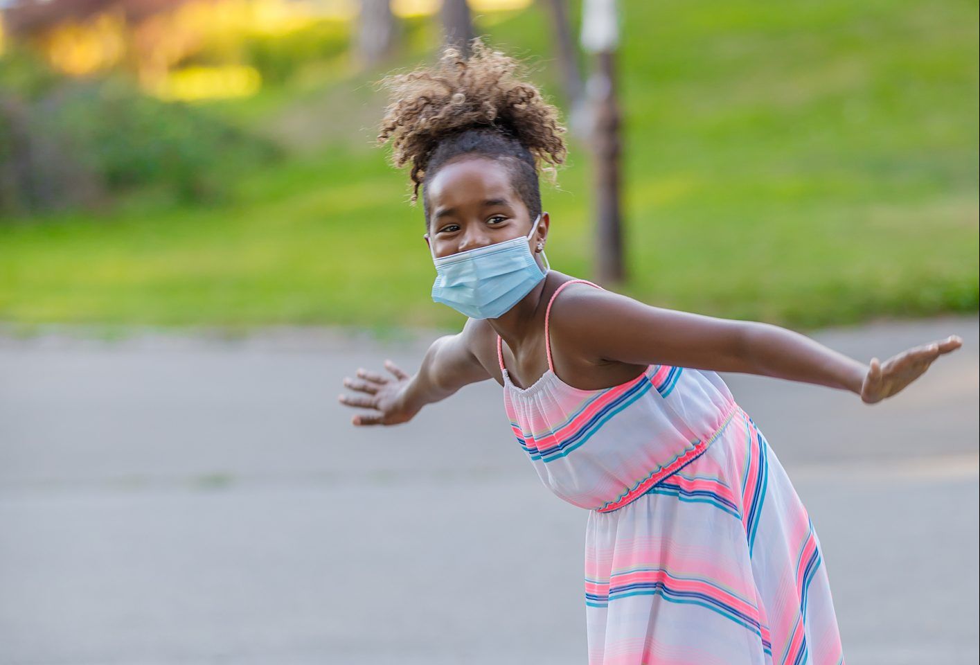 Little African Girl With Protective Mask is Having a Lot of Fun and Riding a Skateboard.