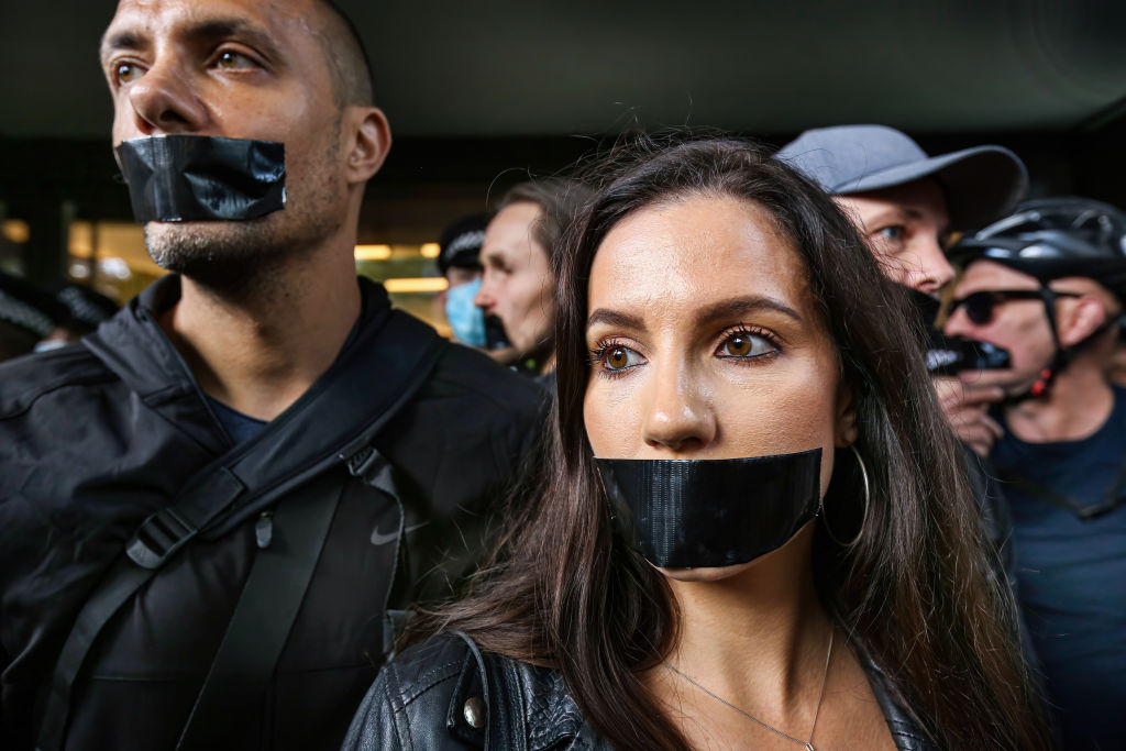 Protesters gather outside Studioworks with black tape on...