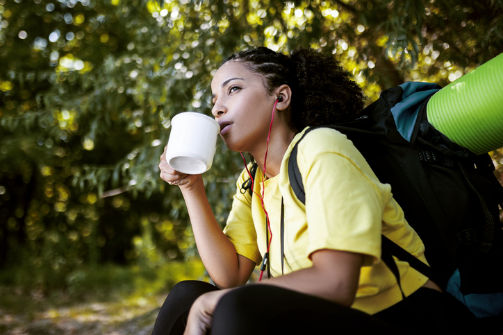 Smiling hiker woman sitting taking a break drinking coffee