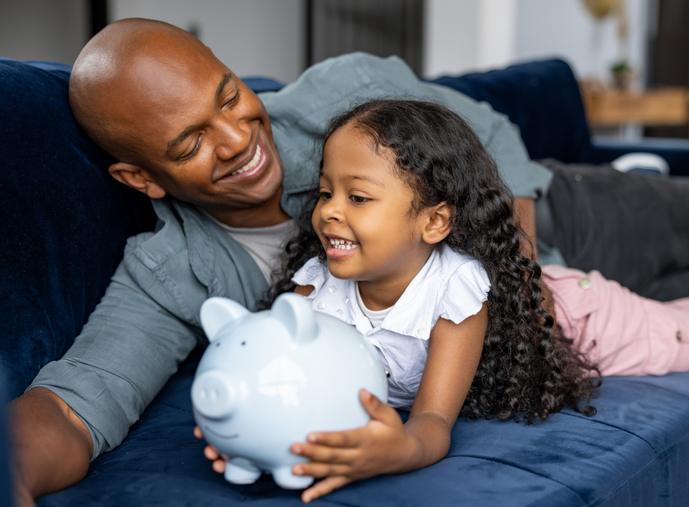 Loving father teaching his daughter to save money in a piggybank