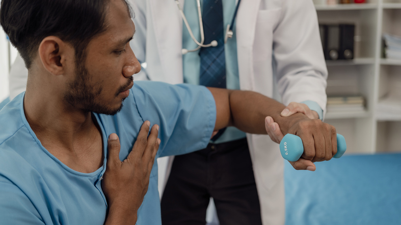 Physical therapist helping a patient while stretching his legs on a bed in a clinic or hospital. Young man attends a physiotherapy course on muscle weakness pain. and heel pain with elastic