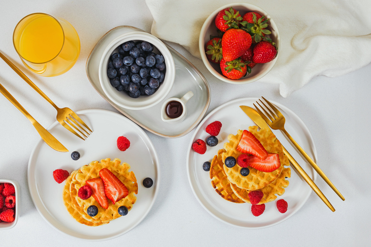 Homemade sweet waffles served with different berries and maple syrup, delicious breakfast
