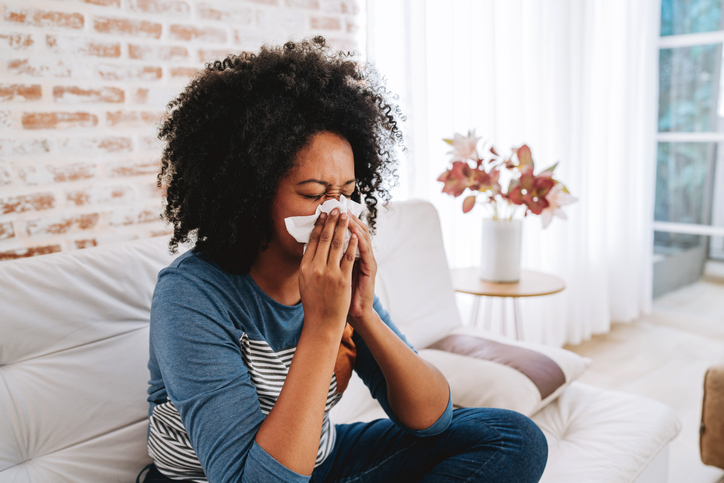 Woman sneezing with a tissue on her nose