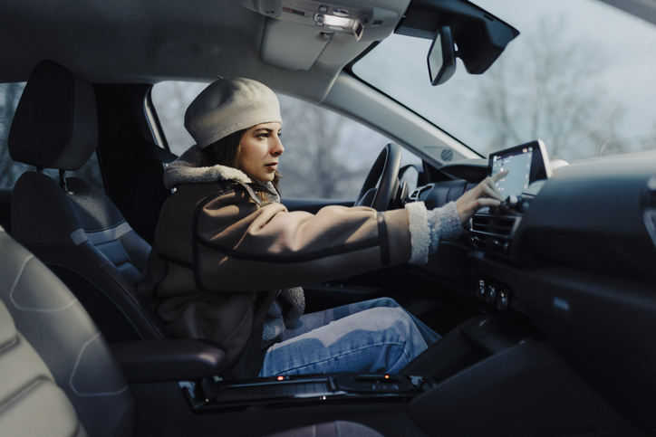 Smiling young woman using global positioning system while driving her car