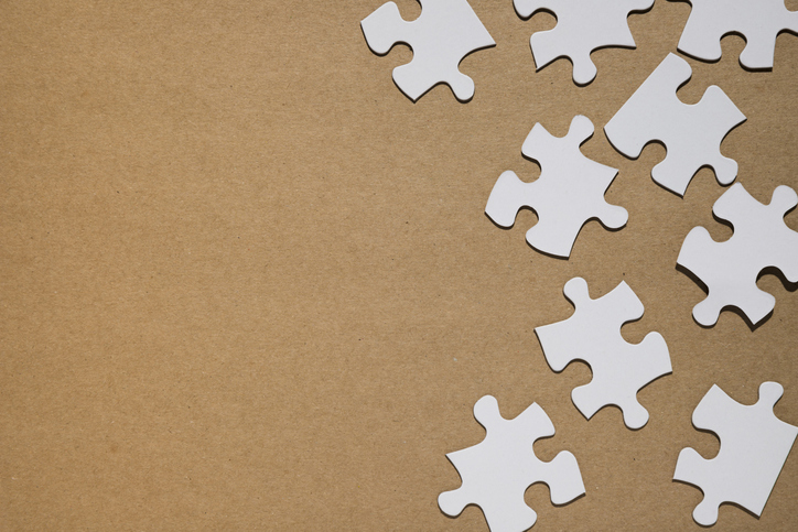 White puzzle pieces brown paper backdrop