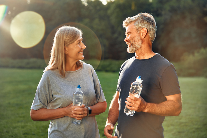 Joyful adults are engaging in delightful outdoor conversations with water bottles in hand