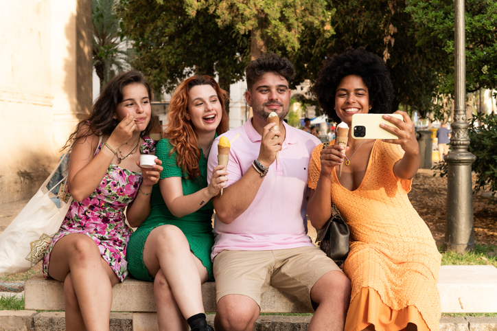 Happy friends taking a selfie while eating ice cream outdoors